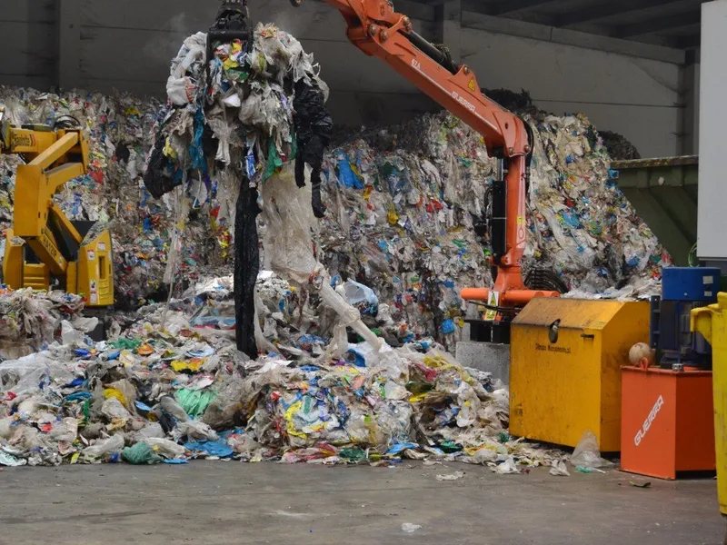 Grúa industrial manipulando pacas de residuos plásticos